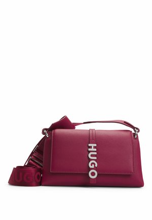 Bolso rectangular de cuero rosa oscuro con solapa, letras plateadas de HUGO en el frente y una correa ancha y desmontable con la marca enrollada a su lado.