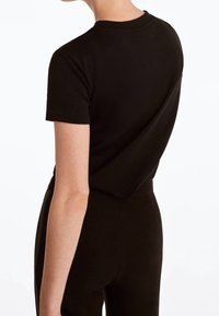 Sort kortærmet t-shirt lavet af bomuld, med rund halsudskæring og en afslappet pasform. Bagsiden er glat uden synlige logoer eller designs.