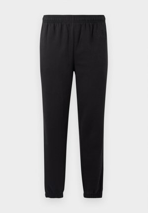 Black sweatpants with elastic waistband, tapered legs, and textured fabric. Features subtle logo detail on the left side.