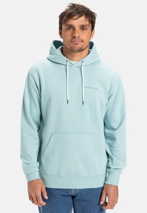 Haut à capuche bleu clair en tissu doux, doté d'une poche avant, de cordons de serrage réglables et d'un logo discret sur la poitrine.