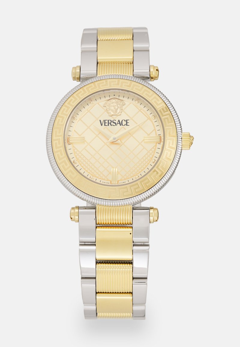 Guld- och silvermetallur med rund urtavla, texturerad guldskiva, grekisk nyckelmönster på bezel och Versace-logotyp. Justerbar armbanddesign.