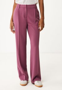 Brede broek in een rijke mauve kleur, met een gestructureerde stof, geplooide plooien en een hoge taille. Gecombineerd met lichtgrijze sneakers.
