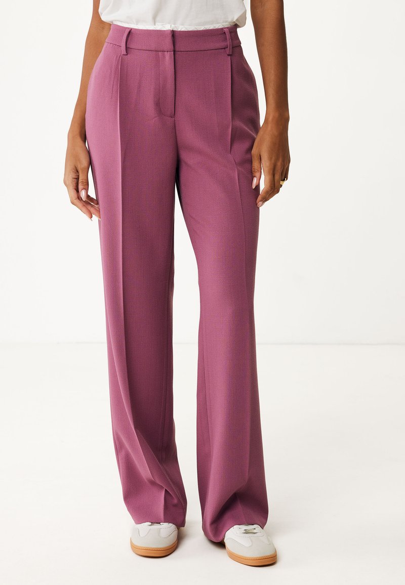 Brede broek in een rijke mauve kleur, met een gestructureerde stof, geplooide plooien en een hoge taille. Gecombineerd met lichtgrijze sneakers.