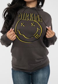Gray hoodie with a large yellow smiley face and "NIRVANA" text. Features a front pocket, drawstrings, and soft fabric texture.