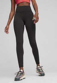 Fekete, magasan szabott leggings, sima, rugalmas anyagból, testéhez szabott kialakítással. Lapított varrásokkal és elegáns sziluettel rendelkezik.