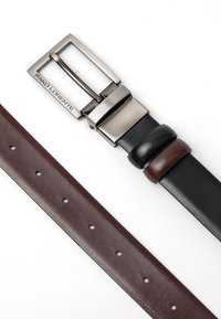 Brązowy i czarny skórzany pasek z metalową srebrną klamrą, z detalami w postaci przeszyć oraz okrągłymi otworami do regulacji rozmiaru.