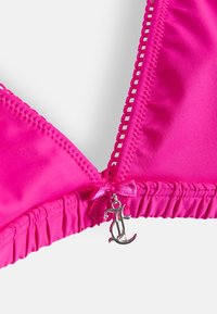 Magenta bikiny vrch vyrobený z hladkej tkaniny, s trojuholníkovým tvarom, nastaviteľnými ramienkami, volánikmi na okrajoch a malým strieborným príveskom.