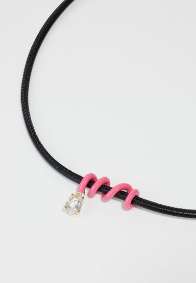 Black rubber choker features a pink spiral accent and a clear, pear-shaped stone set in gold hardware. Smooth texture throughout.