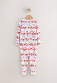 Long-sleeve white pajama set with red hearts and pink bows in a geometric pattern. Soft fabric, includes matching fitted pants.