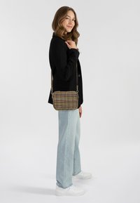 Piccola borsa a tracolla rettangolare con motivo pied-de-poule e rifiniture in marrone e nero. Presenta una tracolla rimovibile e accessori in tonalità dorata.