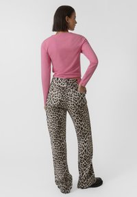 Top de manga larga rosa combinado con pantalones acampanados de leopardo beige. El conjunto presenta un diseño ajustado y una textura suave, adecuado para un estilo casual.