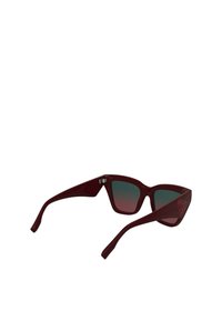 Óculos de sol plásticos cor burdeos com um formato robusto de olhos de gato e lentes verdes em degradê. Apresenta um logótipo subtil na lateral.