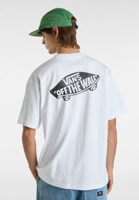 Weißes Baumwoll-T-Shirt mit einem großen schwarzen Grafikdesign eines Skateboards und dem Text "VANS 'OFF THE WALL'" auf der Rückseite. Kurze Ärmel, lockere Passform.