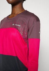 Långärmad träningsskjorta med en färgblockdesign i rosa, svart och mörkbrun. Texturerade mönster och logotyp på framsidan.