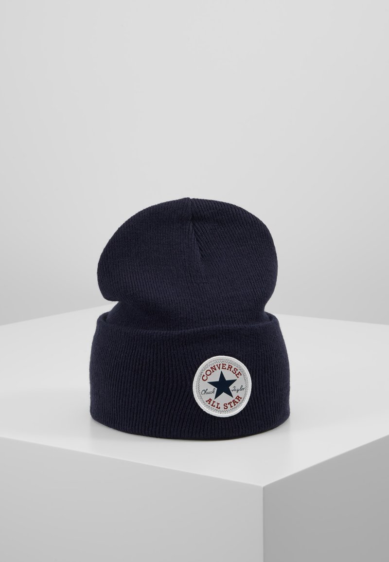 Bonnet en tricot bleu marine avec un revers et un patch rond comportant le texte "CONVERSE ALL STAR" et un motif d'étoile.