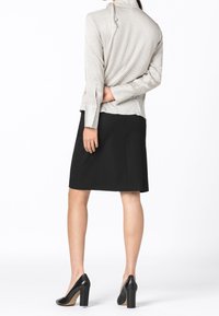 Långärmad, randig blus i ljusbeige och grå. Matchad med en svart penkjol. Svarta högklackade skor fulländar outfiten.