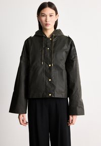 Tume roheline lühike jope kapuutsiga, kuldsete nööpidega, paelaga ja laiade varrukatega. Valmistatud veekindlast materjalist.