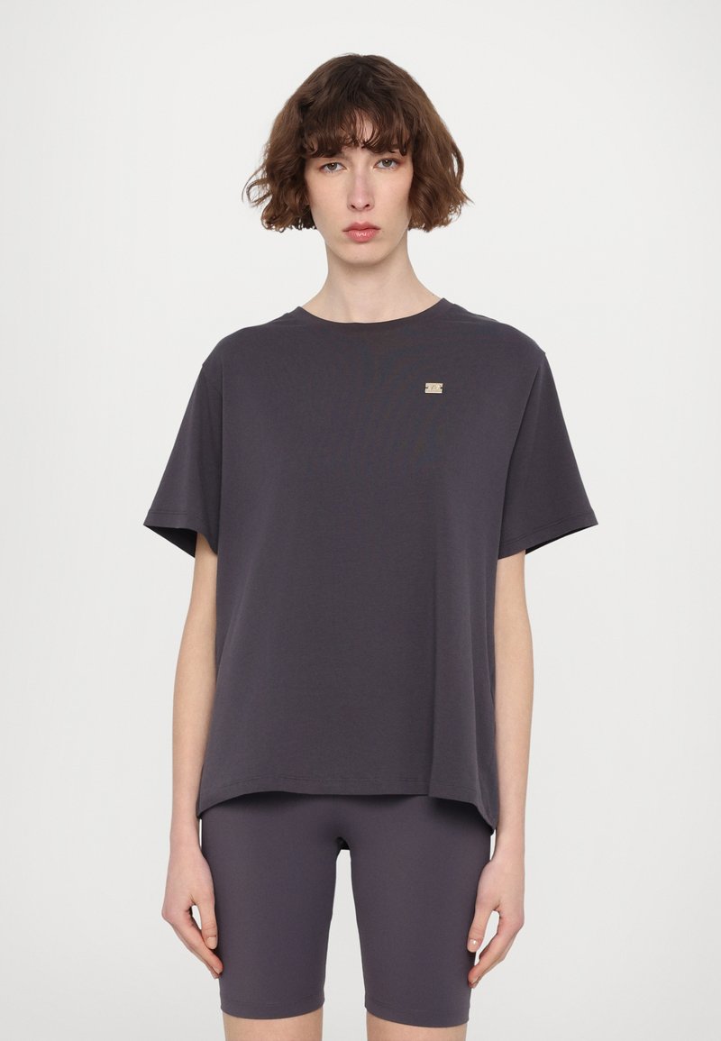 Tricou lejer, gri închis, cu guler rotund și mâneci scurte, având un mic accent de logo metalic pe partea stângă.