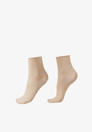 Beżowe półprzezroczyste skarpetki do kostek prezentowane na manekinach stóp, ukazujące elastyczne ściągacze i gładką fakturę na białym tle.