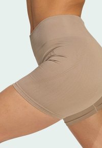 Beige ribbed active shorts with a high waistband, featuring a smooth texture and fitted design. Accents include subtle stitching and seams.