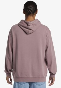 Mikina s kapucňou v mäkkom mauve materiáli s voľným strihom, dlhými rukávmi a rebrovaným lemom. Minimalistický dizajn, bez viditeľných log a vzorov.