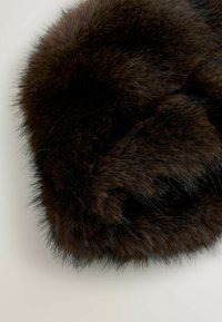 Dunkelbraunes Kunstfell mit einer dichten, weichen Textur. Die Fasern sind lang und flauschig, was eine abgerundete Form mit subtilen Farbvariationen schafft.