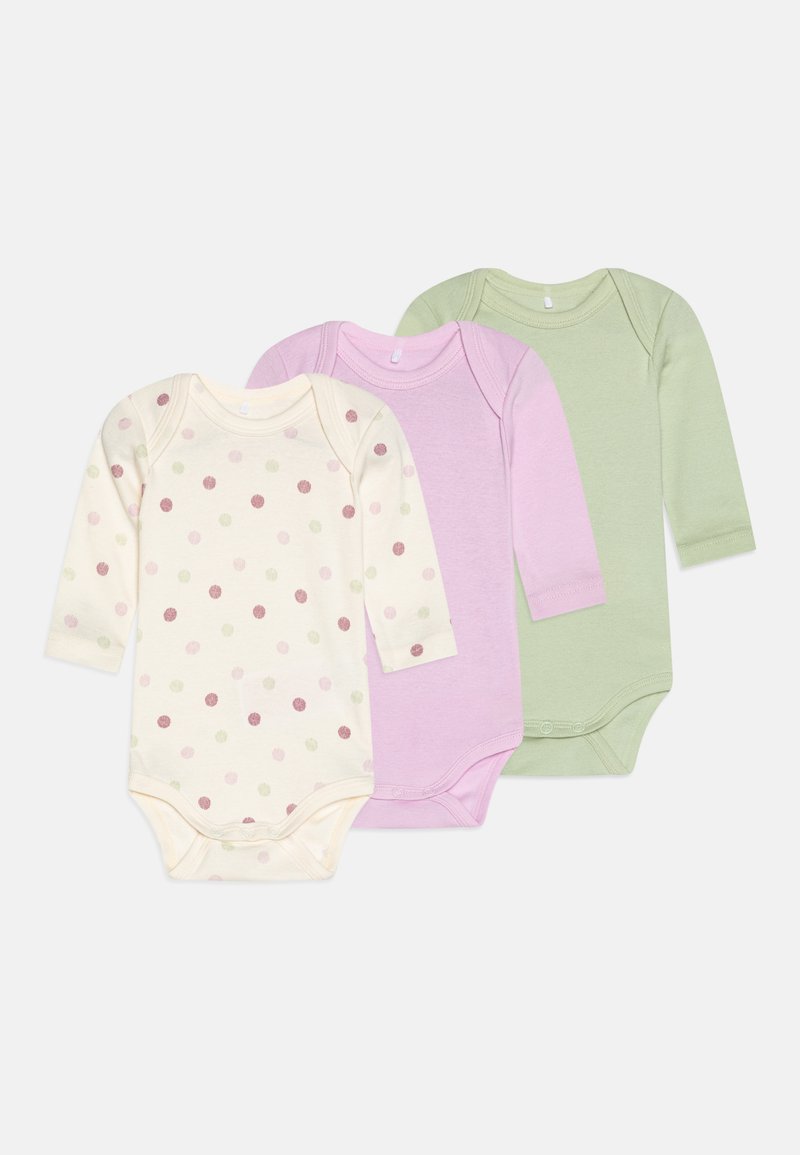 Trois bodysuits à manches longues, présentant un design à pois sur fond crème, un en lavande uni et un en vert clair uni. Tissu en coton doux, fermetures à pression.