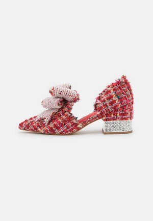 Zapato de tacón en tweed rojo y rosa con un gran lazo en la puntera, que presenta un tacón cuadrado adornado con rhinestones. Diseño de punta afilada.