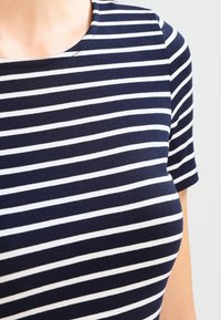 T-shirt bleu marine et blanc à rayures, avec un col rond et des manches courtes, fabriqué en tissu doux et extensible, présentant des rayures horizontales.