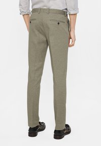 Skräddarsydda olivgröna byxor i texturerad tyg. Har en smal passform, två bakfickor med knappar och bälteshällor.