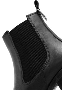 Stivale ankle in pelle nera con pannelli laterali elasticizzati, superficie liscia, punta arrotondata e una linguetta per indossarlo facilmente. Dettagli di cucitura discreti.