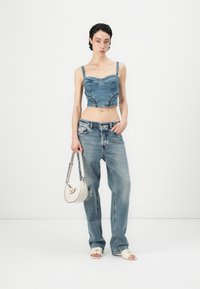 Denim īsais topiņš ar bustiera dizainu un mežģīņu akcentiem, kombinēts ar gaiši ziliem izsistiem džinsiem. Baltā somiņa ar sudraba detaļām.