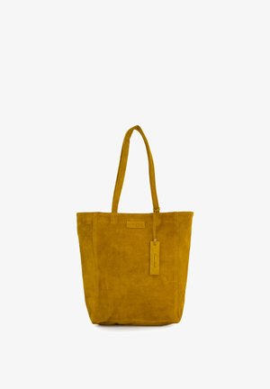 Okergele suède handtas met twee lange hengsels en een rechthoekige label die aan één van de hengsels hangt.