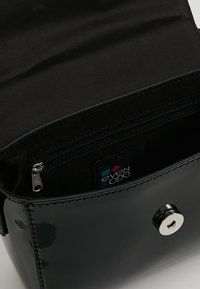 Borsa in pelle verniciata nera con una finitura liscia, dotata di una tasca con zip all'interno e una chiusura a scatto. Etichetta del marchio visibile all'interno.