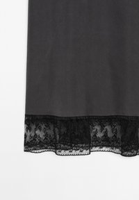 Black fabric with a smooth texture, featuring a lace hem at the bottom with intricate floral patterns and scalloped edges.