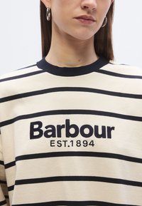 Crème gestreepte sweatshirt met marineblauwe strepen, met geborduurd "Barbour EST. 1894" logo, ronde hals en een gladde textuur.