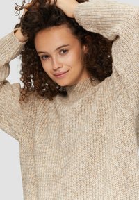 Beige gestrickter Pullover mit hohem Kragen, strukturiertem Stoff und lockerer Passform. Verfügt über weite Ärmel und ein weiches, gemütliches Aussehen.