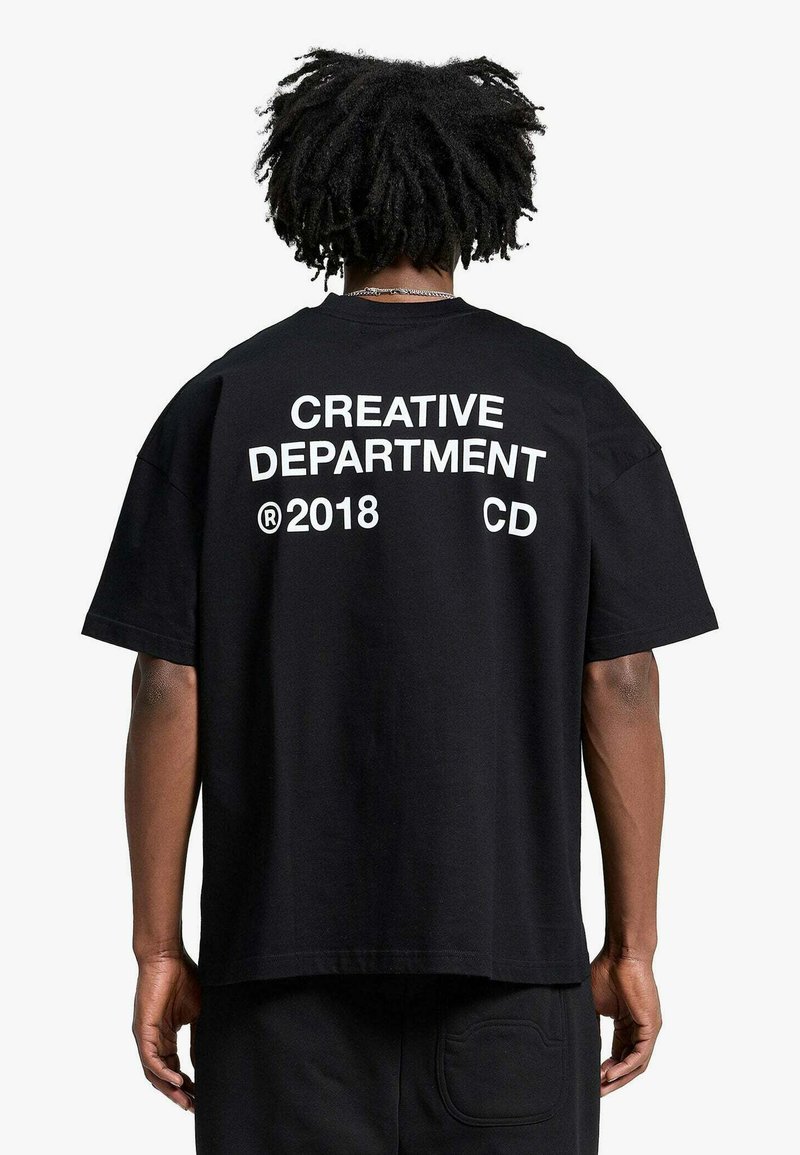 T-shirt nera in cotone con testo bianco stampato sul retro: "CREATIVE DEPARTMENT 2018 CD." Vestibilità ampia con maniche corte.