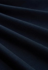Marineblauer Stoff mit glatter Textur, der Wellen und Falten zeigt. Das Material wirkt weich und leicht elastisch, ohne Muster oder Akzente.