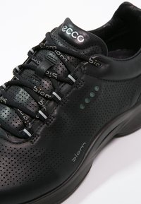 Le sneaker Ecco nere presentano una parte superiore in pelle perforata con lacci rotondi, un colletto imbottito e una suola in gomma con sottili accenti verdi.