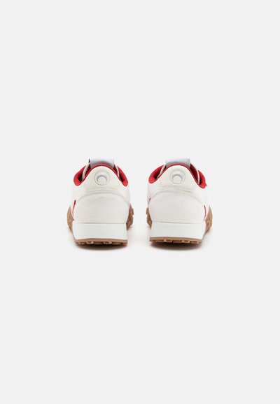 White and red sneakers with a textured suede finish, rounded design, rear pull tab, and gum rubber outsole. Two circular logo accents on heels.