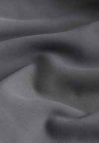 Glat mørkegråt stof med bløde folder og subtil tekstur under diffust lys.