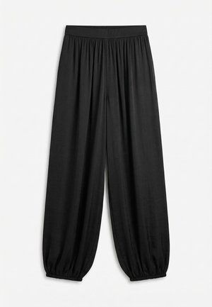 Pantalon noir ample avec taille élastique froncée et poignets élastiques, fabriqué en tissu léger et fluide.