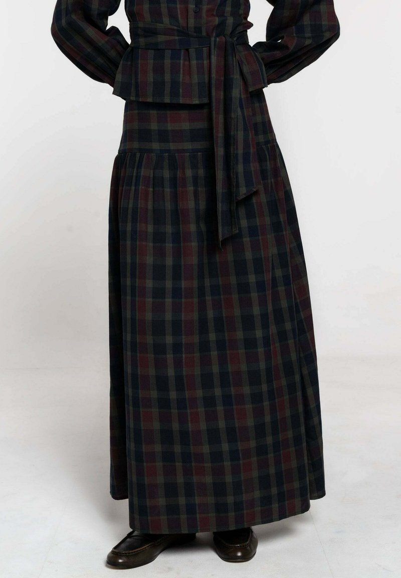 Robe longue à carreaux avec une taille peplum ; couleurs marine, verte et bordeaux. Elle possède des manches longues, une taille knotée et une jupe fluide.