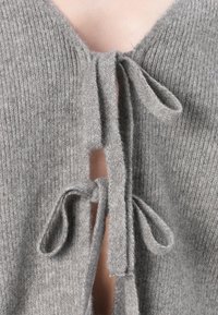 Γκρι πλεκτό πουλόβερ με V-λαιμόκοψη, ανοιχτό μπροστινό μέρος με δεμένο κλείσιμο και υφή υφάσματος με εμφανή ραφή.