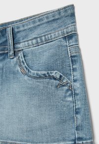 Light blue denim fabric with front pocket, belt loop, and visible stitching details, highlighting classic jeans design and texture.