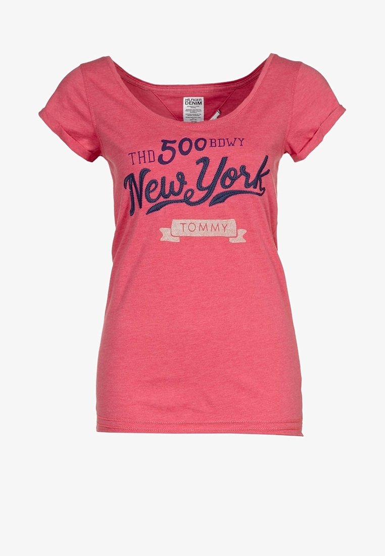 Camiseta de algodón rosa con mangas cortas y escote redondeado. Presenta "Nueva York" en azul marino, con "TOMMY" debajo en blanco sobre una pancarta decorativa.
