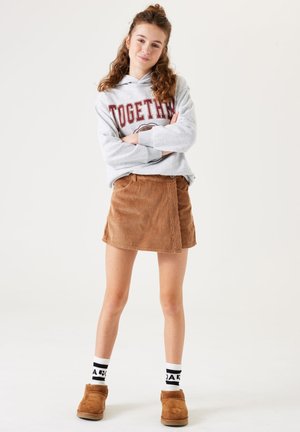 Grijze hoodie met de tekst "TOGETHER", bruine corduroy rok, witte sokken met zwarte accenten, tan enkelboots. Korte en strakke pasvorm.