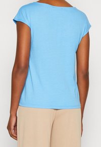 Světle modré tričko s krátkým rukávem, kulatým výstřihem a měkkou texturou. Spodní lem je mírně zaoblený, navržený pro neformální nošení.