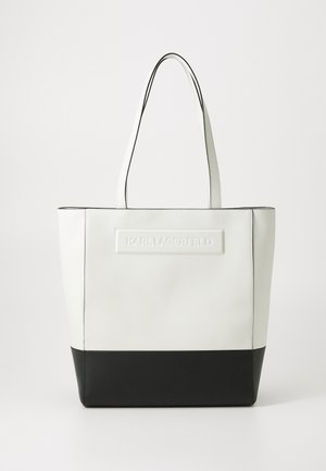 Witte leren tote bag met een zwarte bodem. Voorzien van een reliëflogo aan de voorkant, dubbele handvatten aan de bovenkant en een stijlvolle, gestructureerde vormgeving.